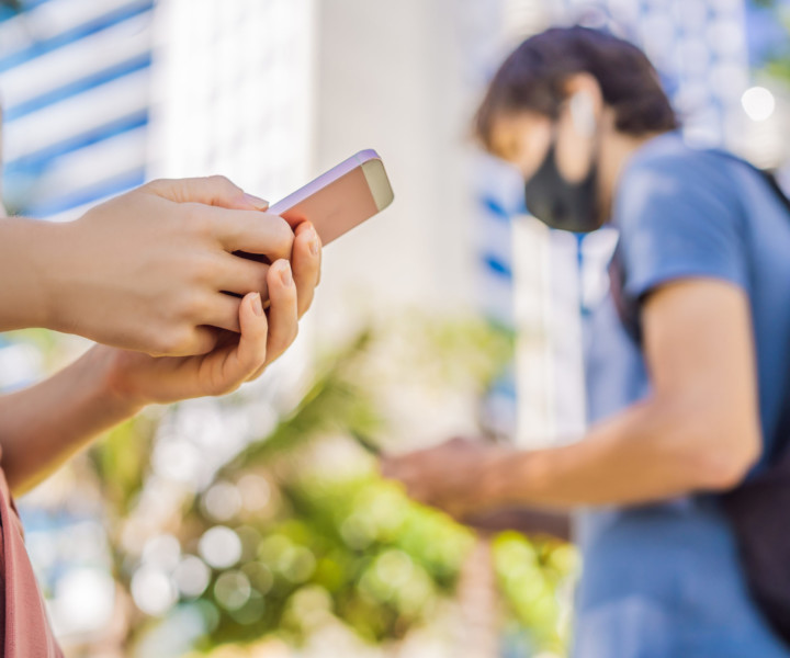 contact tracing app COVID-19 pandemic coronavirus mobile application. people wearing face mask using smart phone app in city street to aid contact tracing in response to the 2019-20 Coronavirus Pandemic.