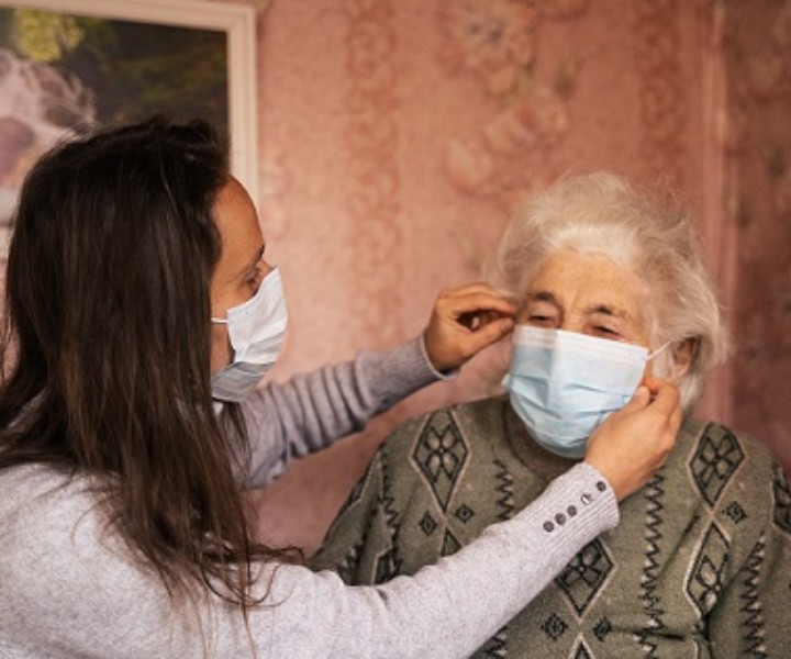 Young woman with her grandmother, discussing the coronavirus. Both with protective masks on their face.