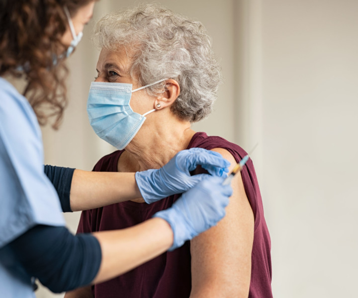 General practitioner vaccinating old patient in private clinic with copy space. Doctor giving injection to senior woman at hospital. Nurse holding syringe and using cotton before make Covid-19 or coronavirus vaccine.