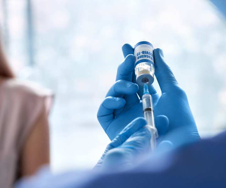 Male doctor wearing gloves holding syringe taking coronavirus vaccine dose from vail preparing for covid 19 vaccination for patient. Flu influenza vaccine clinical corona virus treatment close up view