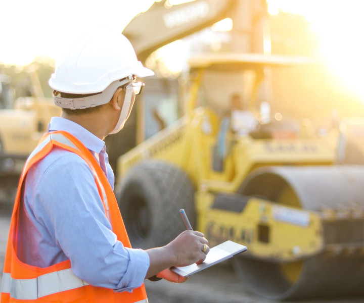 Asian engineer with hardhat using  tablet pc computer inspecting and working at construction site