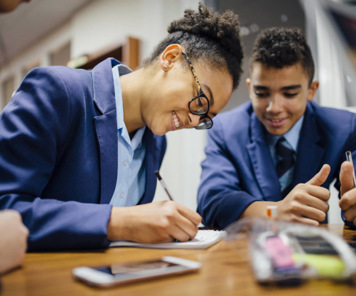 Teen students are working together and taking notes in lesson time at school.