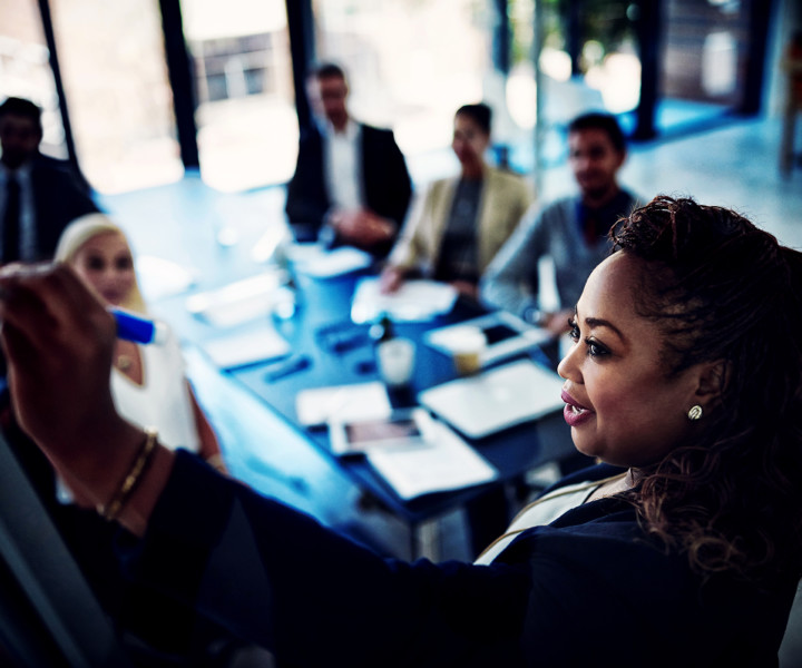 High angle shot of a young businesswoman explaining work related stuff during a presentation to work colleagues in a boardroom