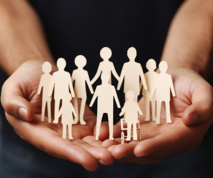Person is seen holding paper cutout of family. This versatile image can be used in various contexts, such as family, relationships, diversity, or even advertising campaigns promoting unity and togetherness.