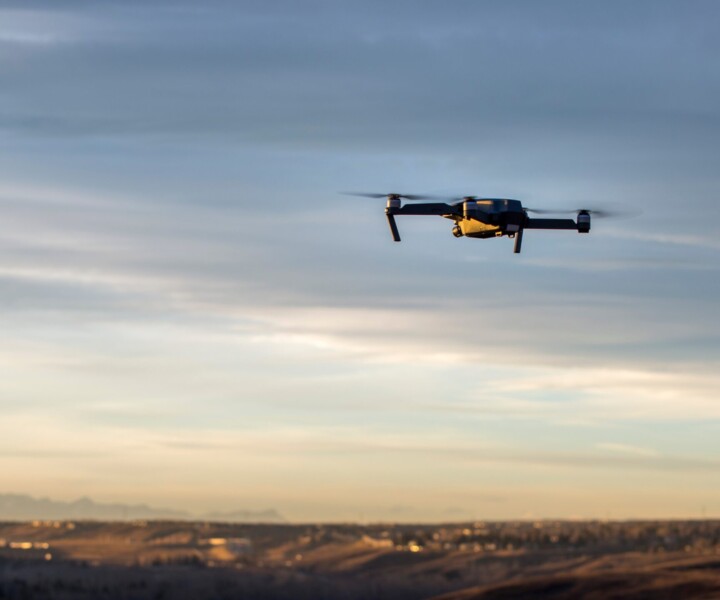 Small modern drone hovering taking picture of sunset